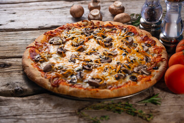 Pizza with mushrooms and cheese on a wooden background