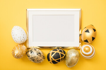 Frame with gold decorated easter eggs with copy space for text on yellow background. Minimal Happy Easter concept. Top view, flatlay