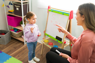 Female tutor speaking with a beautiful preschooler at home