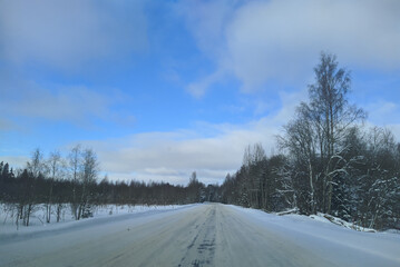 Fototapeta na wymiar road with horizon on blue sky and clouds in the daytime at winter with snow covered trees