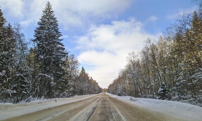 Obraz premium highway with horizon on blue sky and clouds in the daytime at winter with snow covered trees