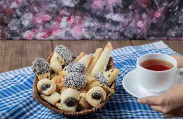 Chocolate sesame cookies in a wooden basket with a cup of earl grey tea