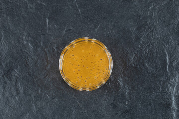 A glass of yellow orange juice on black background