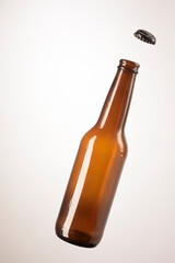 Botella de cerveza artesanal, vacía con corcholata volando
