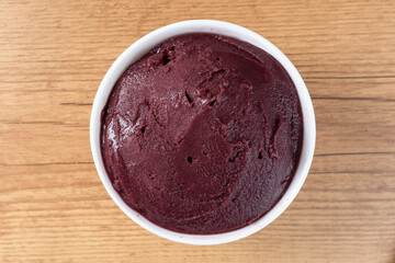 Brazilian frozen açai berry ice cream bowl. with fruits on wooden background. Summer menu top view