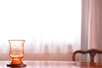 “art deco” crystal vase.  put on a walnut oval dining table.
window is bright. 

This expensive antique furniture is made in England. 
clear background with soft focus image.