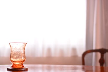 “art deco” crystal vase.  put on a walnut oval dining table.
window is bright. 

This expensive antique furniture is made in England. 
clear background with soft focus image.