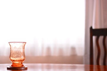 “art deco” crystal vase.  put on a walnut oval dining table.
window is bright. 

This expensive antique furniture is made in England. 
clear background with soft focus image.