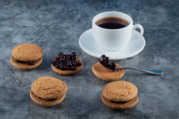 Oatmeal cookies with blackcurrant berries confiture served with a cup of tea