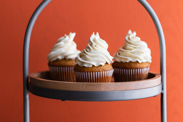 Frosted sweet potato cupcakes sitting on a pastry stand.
