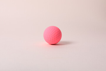 a golf ball of various colors with a pink background