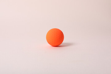 a golf ball of various colors with a pink background