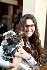 Adorable Pug, pulls the hair of a young woman