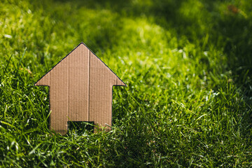 green home and eco-friendly construction, house icon on green grass lawn under the sun with garden bokeh