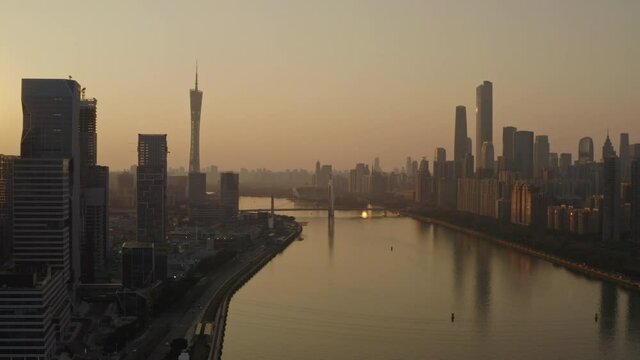 Fly over Pearl River with with downtown office buildings on the banks of the river at a beautiful colorful golden sunset. Guangzhou, Guangdong, China.