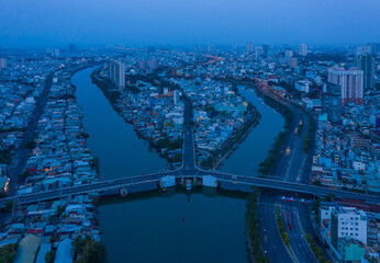 Aerial view of symmetrical french colonial traffic bridge at night across a canal in urban area with blue treatment