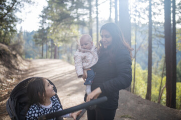 Happy woman holding her adorable baby in the forest