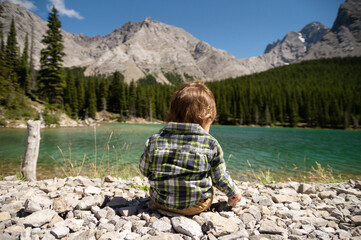 Baby sitting on rocks by Elbow lake on a sunny Summer day in the backcountry