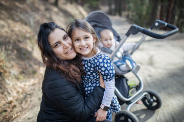 Fototapeta na wymiar Happy woman with her adorable young daughters in the forest