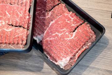 Raw Beef sliced for Shabu or Sukiyaki in black plate.