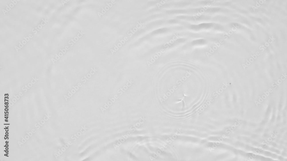 Poster Close up top view of water droplets falling into the water and separate splashes of water on gray background in 4k slow motion.