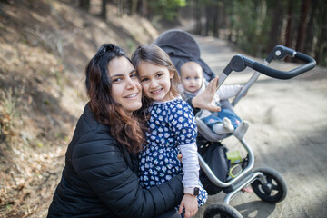 Obraz premium Happy woman with her adorable young daughters in the forest