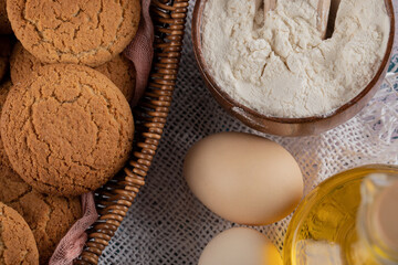 Oatmeal cookies in a wooden basket tray with ingredients around