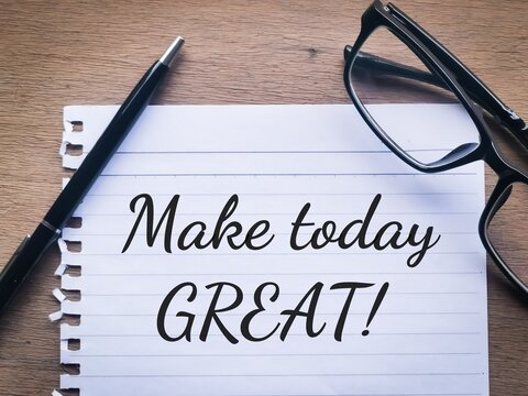 Phrase MAKE TODAY GREAT written on a piece of paper with a pen and eye glasses. Motivational quote.