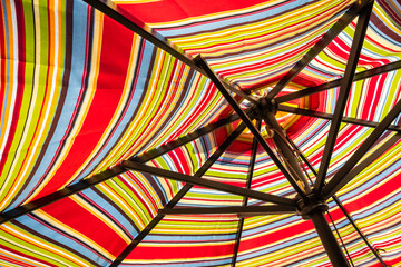 Abstract background with stripes...striped patio umbrella from the underside in the sun.