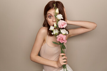 Happy woman with a bouquet of light flowers on a beige background naked shoulders model red hair beautiful face