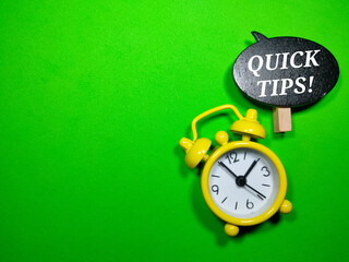Fototapeta premium Selective focus.Alarm clock and wooden board with written text QUICK TIPS.Business concept.Shot were noise and film grain.