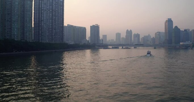 View of Guangzhou Pearl river with River tour boats sailing along the river and numerous office building on the side of the river. Guangdong, China. Aerial shot.