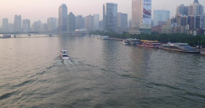 Guangzhou Pearl River tour boat sailing along the river with living apartment and office buildings on the river sides in the afternoon. Aerial shot.