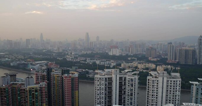 View of Guangzhou living blocks by the river side and far in the distance in late afternoon. Guangdong, China.