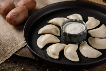 Appetizing traditional Russian dumplings, hand-made with potatoes. Still life on a wooden board. Close-up.