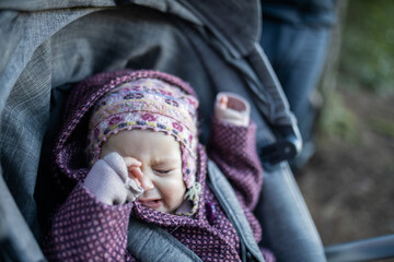 Adorable crying baby in a stroller with blurry background