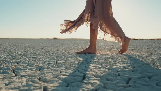 adult woman walking barefoot on bottom of dried lake ,stepping on cracked soil ground.  global warming 4K .