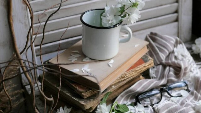 Still life with an old book, a metal mug and white flowers. composition in a rustic style.