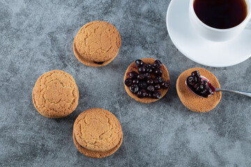 Oatmeal cookies with blackcurrant berries confiture served with a cup of tea