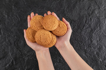 A chef holding oatmeal cookies in the hand