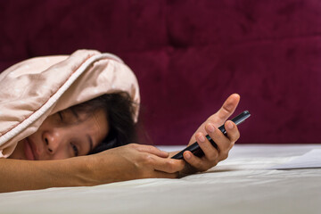 Asian women cannot awake from bed and trying to press stop alarm clock from phone