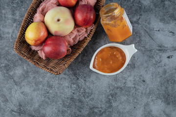 Peach and apples in a wooden basket on a piece of pink towel 