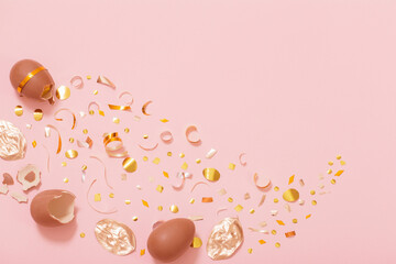 Easter chocolate egg with golden confetti on pink background