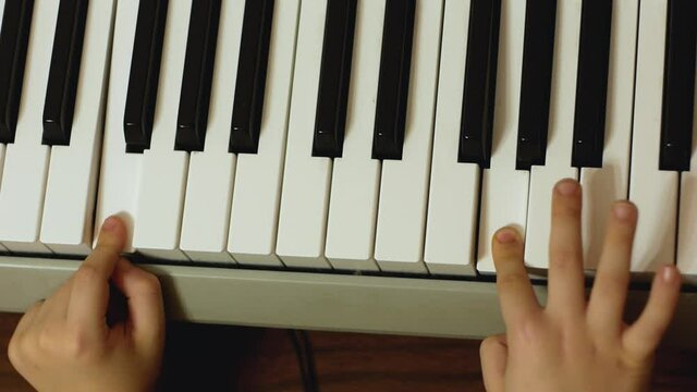 Teaching a child to play a musical instrument theme. Close-up of childrens fingers playing the piano. Development of musical talent in a child. Selective focus