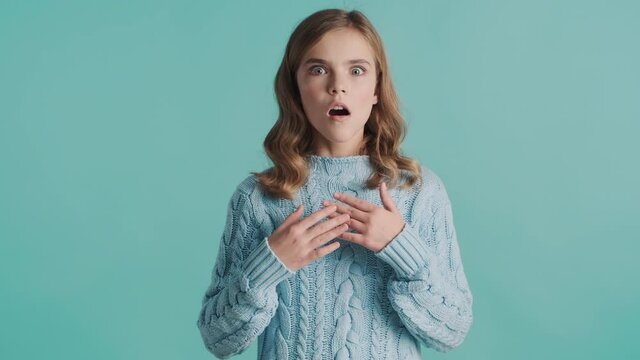 Amazed blond teenager girl looking astonished over blue background. Wow face expression