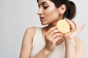 Beautiful brunette holding a sponge in her hands clean health skin close-up