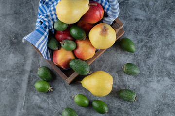 A wooden fruit tray full of pears, feijoas and peaches
