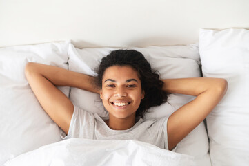 Happy young mixed-race woman with curly hair cheerfully smiling, looking at the camera, waking up,...