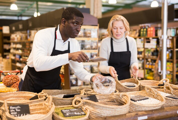 Friendly African man working in bulk food department of supermarket..