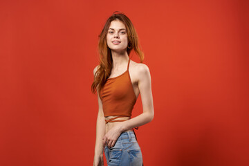 cheerful woman in red t-shirt and jeans glamor studio red background